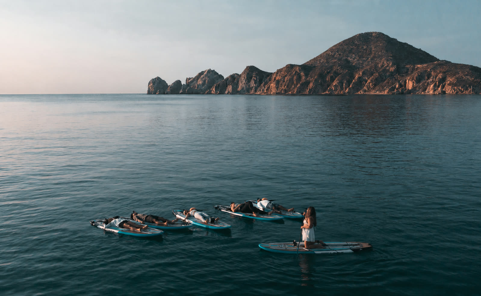 Clase de yoga en paddle board frente al Arco al amanecer